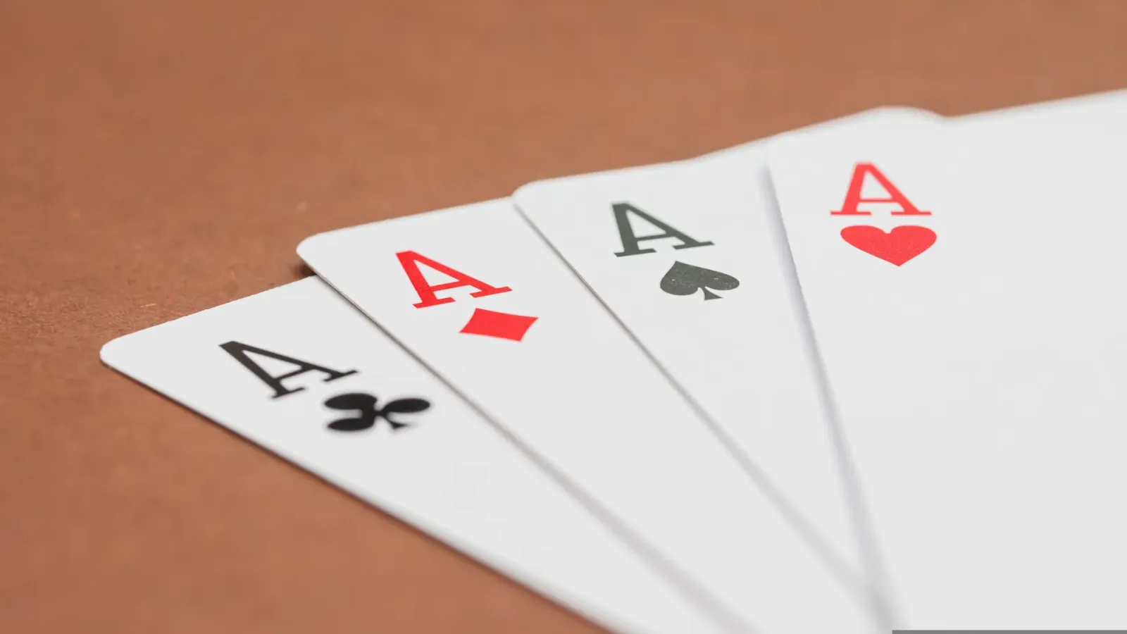 Four aces fanned out on a brown table