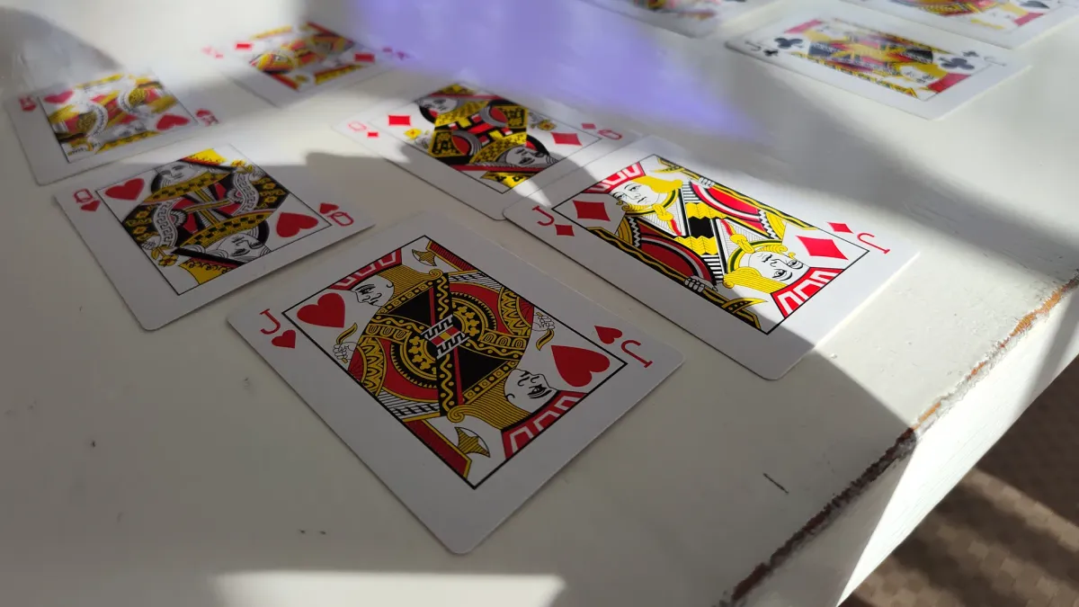 Jacks, queens and kings laid out on a white table in sunlight