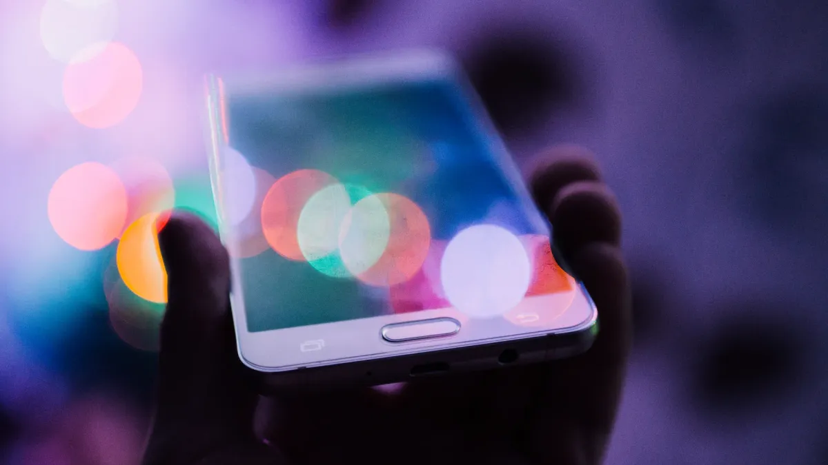Smartphone held in hand against colourful bokeh lights