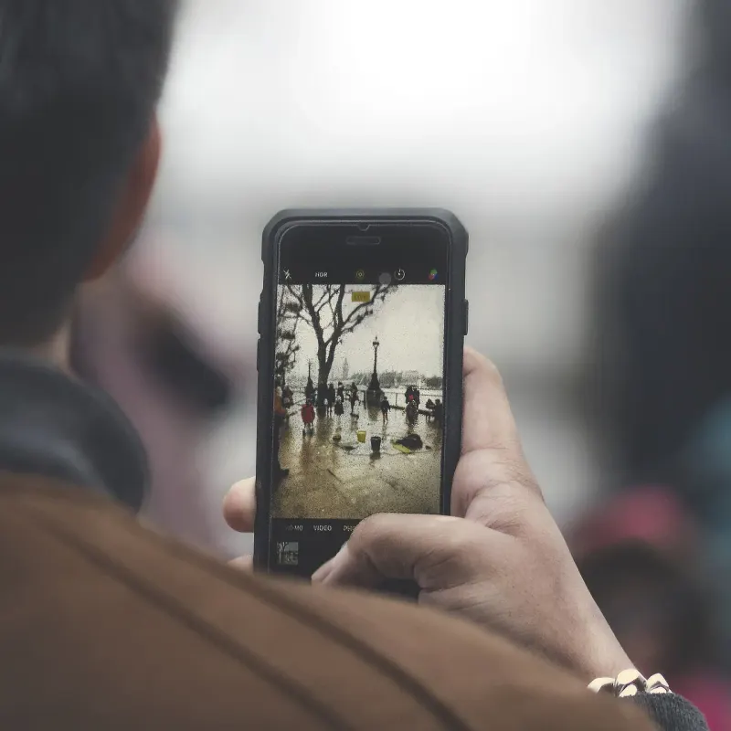Person seen from behind taking a photo on a smartphone