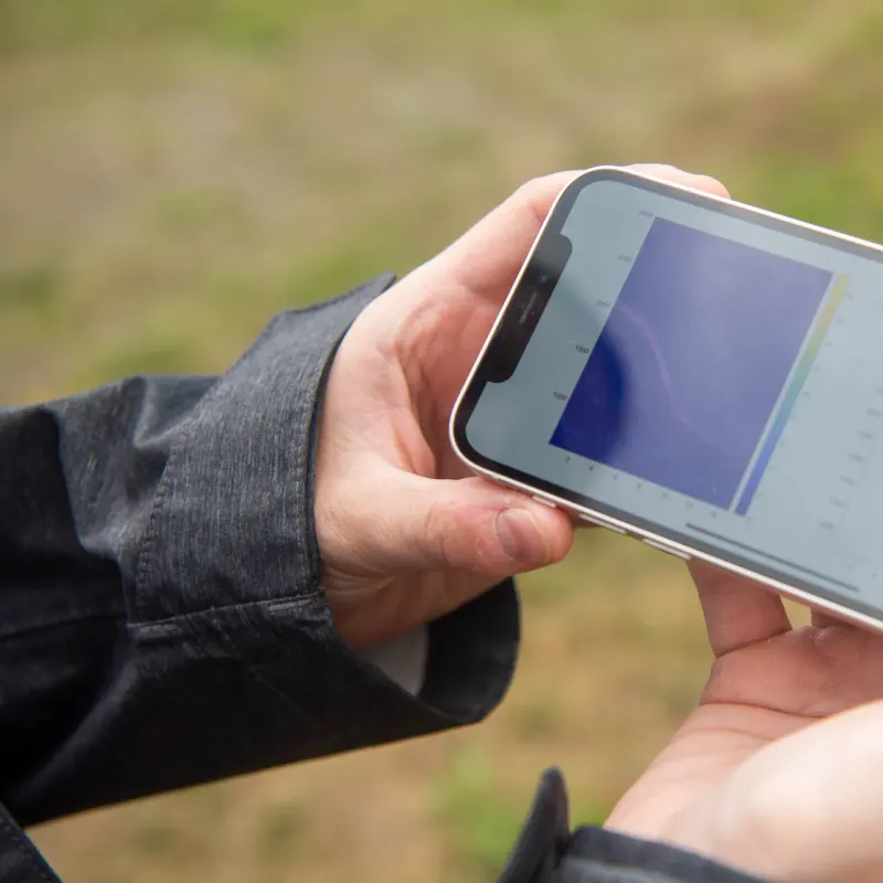 Two hands holding a smartphone sideways outdoors